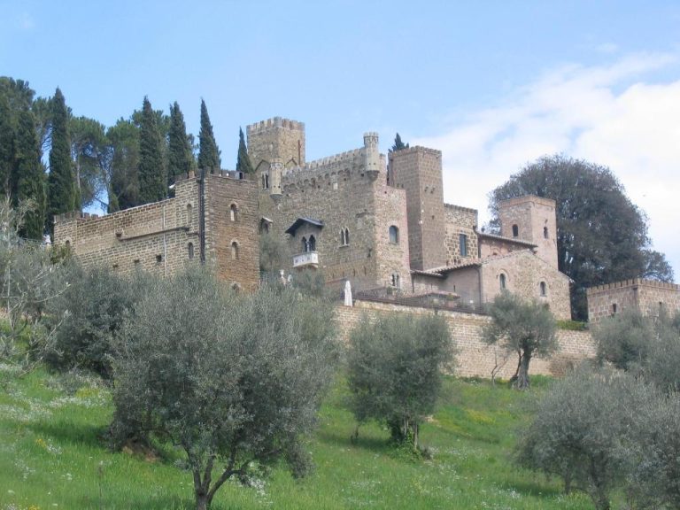 Fachada exterior medieval del Castello di Monterone en Perugia rodeado de olivos y vegetación toscana