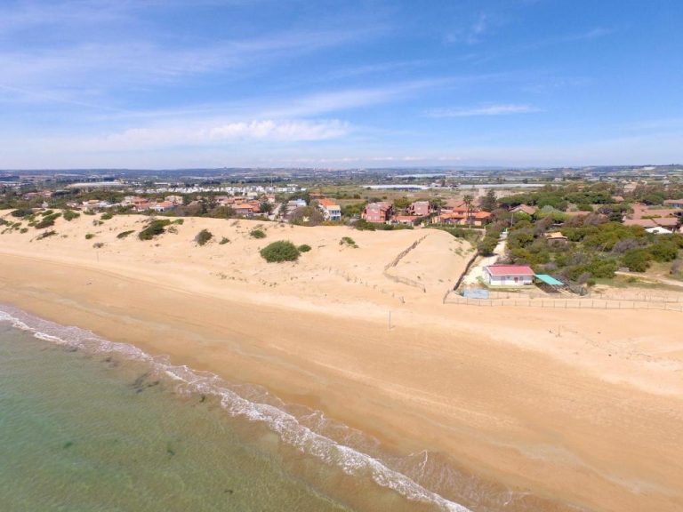 Vista aérea de la playa y dunas de arena junto a Le Dune Residence con mar turquesa
