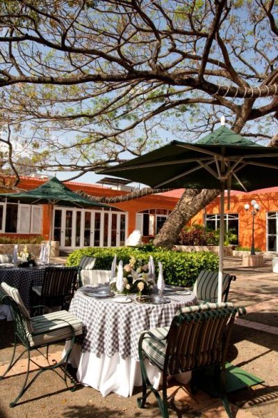 Terraza exterior del restaurante del Hotel Globales Camino Real Managua con mesas y sombrillas verdes
