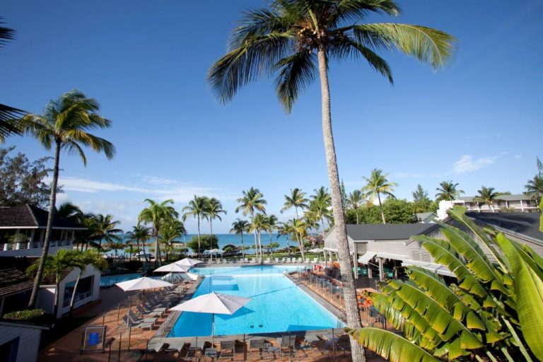 Piscina exterior con palmeras y vistas al mar del Mahogany Hotel Residence & Spa