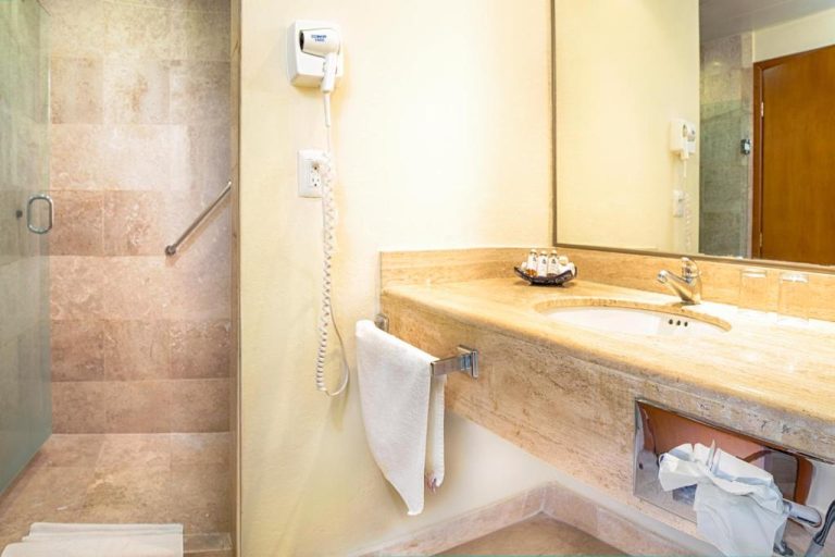 Baño moderno con ducha de mármol, lavabo y secador de pelo en Hotel Los Itzaes by 5th Av