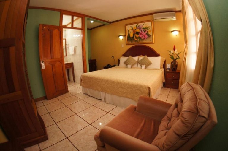 Habitación doble con cama matrimonial y sillón en Hotel Cafe, decoración tropical y baño privado