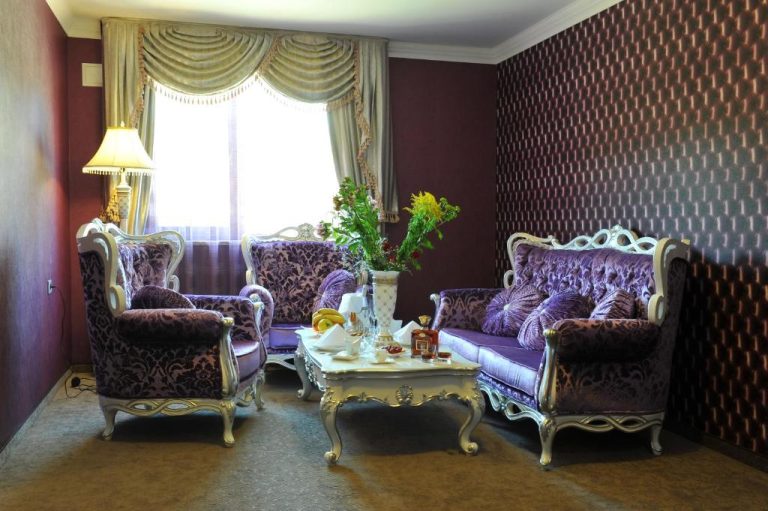 Elegante salón de suite con sofás de terciopelo violeta y mesa de centro clásica en Park Hotel Stara Zagora