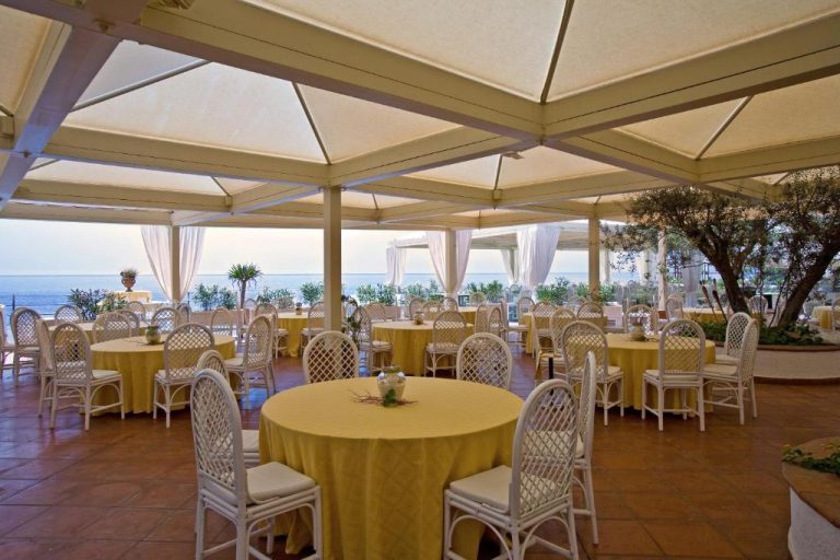 Terraza restaurante con mesas amarillas y vistas al mar en el Grand Hotel Baia Verde