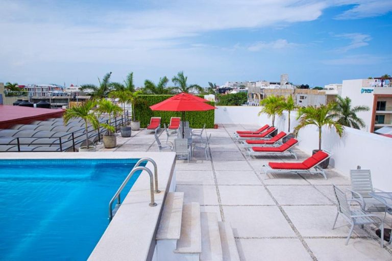 Piscina exterior con solarium y tumbonas rojas en Hotel Los Itzaes by 5th Av en Playa del Carmen