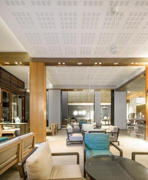 Elegante lobby lounge del Eden Bleu Hotel con sofás blancos, sillas de madera y decoración moderna