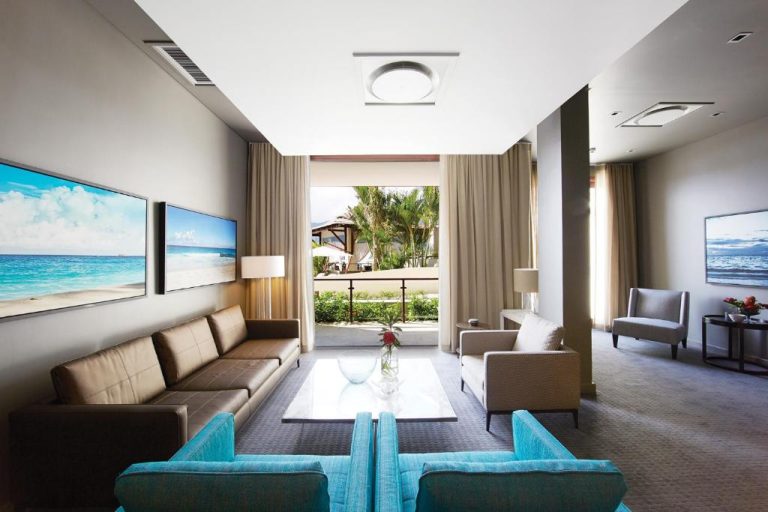Amplio salón de suite con sofás de cuero y vistas a jardín tropical en Eden Bleu Hotel