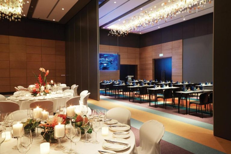 Salón de eventos y banquetes con mesas decoradas y velas del Eden Bleu Hotel