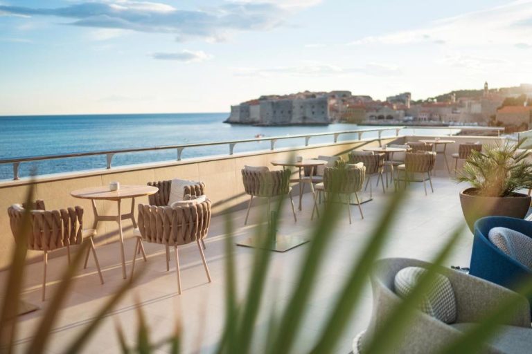 Terraza exterior del Hotel Excelsior con mesas y vistas al mar Adriático y la ciudad vieja de Dubrovnik