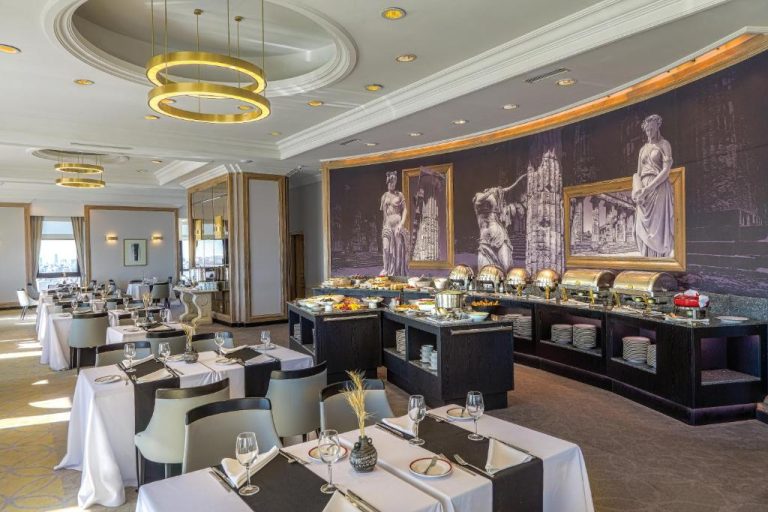 Restaurante buffet con murales clásicos y mesas elegantes del Radisson Montevideo Victoria Plaza Hotel