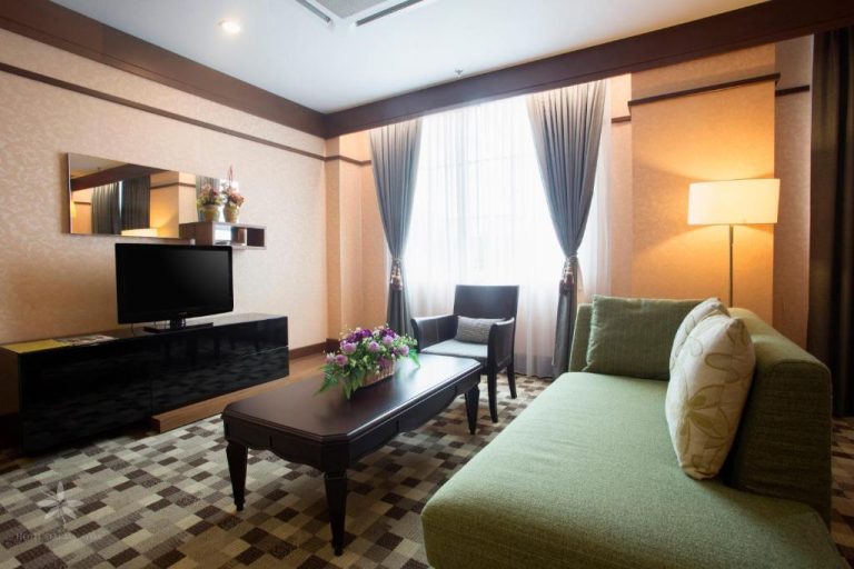 Salón elegante de la suite del Hotel Seri Malaysia Lawas con sofá verde, TV y decoración moderna