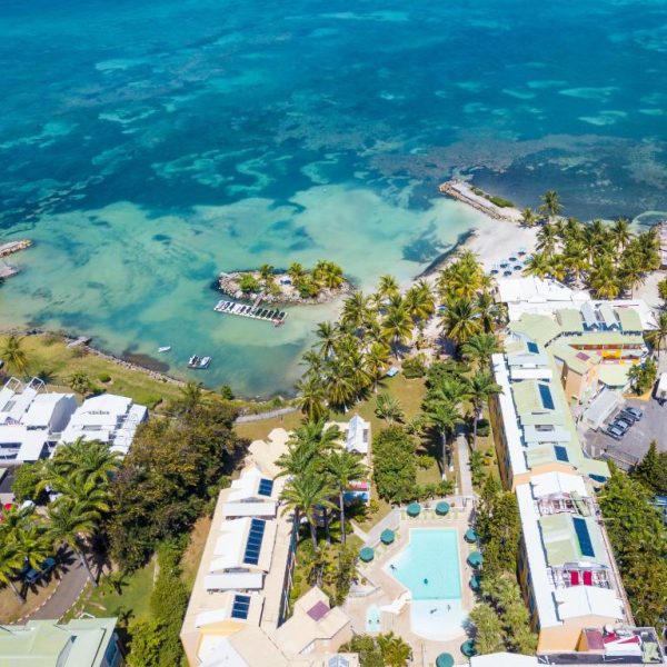 Vista aérea del Canella Beach Hotel con piscina exterior, palmeras y acceso directo a la playa de aguas turquesas