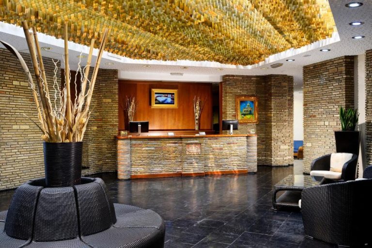 Recepción y lobby del UNA Hotels Capotaormina con techo dorado decorativo y paredes de piedra