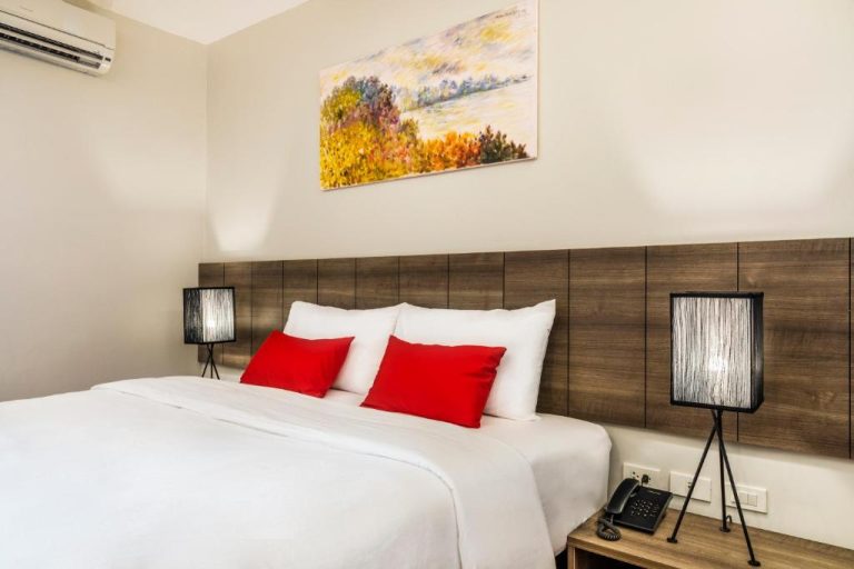 Habitación doble con cama king, almohadas rojas y cabecero de madera en Livotel Hotel Hua Mak Bangkok