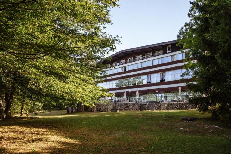 Fachada exterior del Hotel Jezero rodeada de jardines y árboles en el Parque Nacional de los Lagos de Plitvice