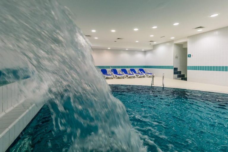 Piscina interior con cascada de agua y tumbonas azules del Hotel Jezero en el Parque Nacional de los Lagos de Plitvice