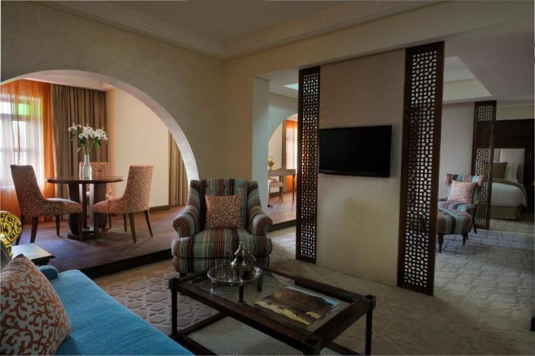 Suite de lujo con salón, arcos decorativos y separadores de madera estilo árabe en Souq Waqif Boutique Hotels Tivoli
