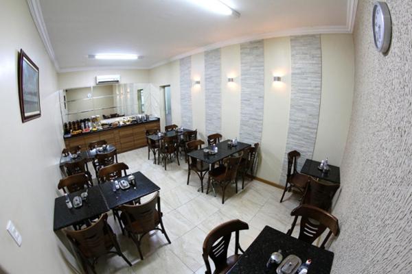 Comedor interior del Hotel Belem Fortaleza con mesas negras y sillas de madera elegantes