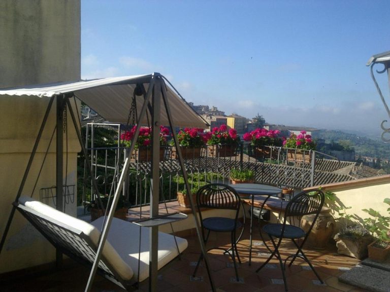 Terraza con hamaca, mesas y flores del Primavera Mini Hotel con vistas panorámicas a la ciudad