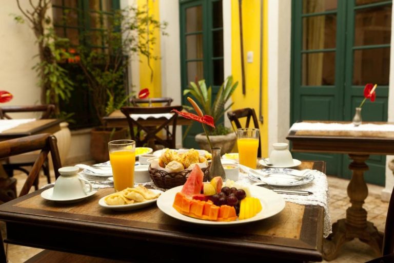 Desayuno buffet con frutas tropicales y zumo de naranja en el patio colonial del Hotel Villa Bahia
