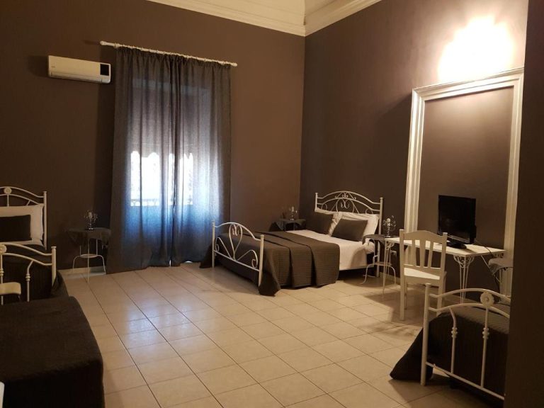 Habitación doble con camas individuales de hierro forjado blanco y suelo de mármol en Hotel Biscari