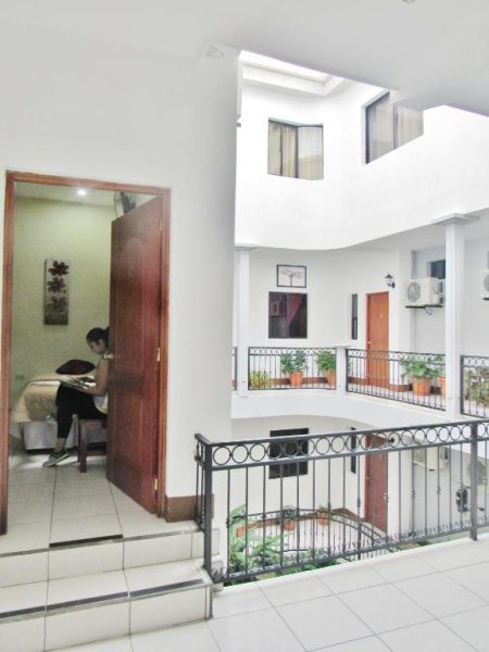 Pasillo interior con balcón y barandilla del Hotel Palmeras de Elim con habitaciones y patio central