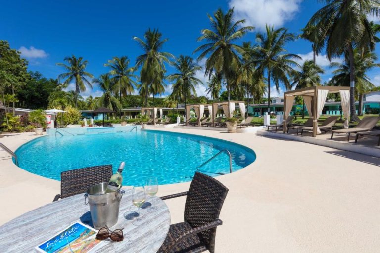 Piscina exterior con tumbonas y palmeras tropicales del All Seasons Resort bajo cielo azul
