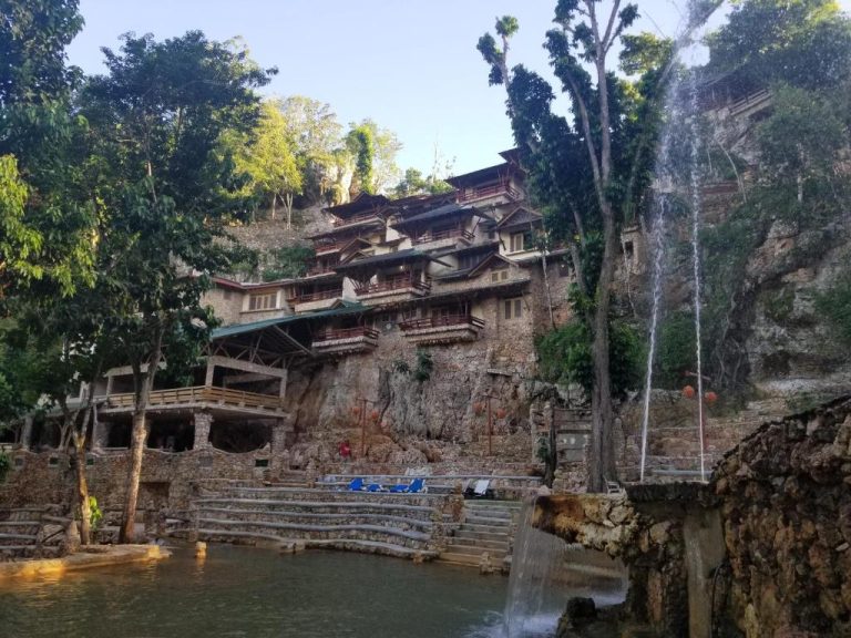 Piscina natural con cascada y edificio en la roca del hotel Paraíso Caño Hondo en República Dominicana