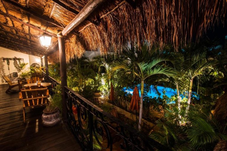 Terraza colonial con techo de palapa y vista a la piscina iluminada en La Pasion Colonial Hotel Boutique By Bunik