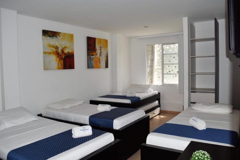 Habitación múltiple con cuatro camas individuales y decoración moderna en Hotel Travelers Sport