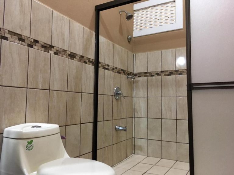 Baño con ducha de azulejos beige y sanitario en Hotel Hacienda El Rodeo