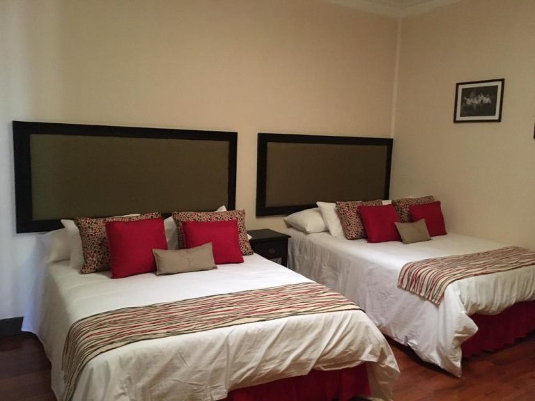 Habitación doble con dos camas y cojines rojos en Hotel Hacienda El Rodeo