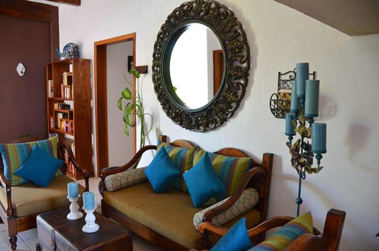 Sala de estar colonial con sofá, cojines azules y espejo decorativo en La Pasion Colonial Hotel Boutique By Bunik