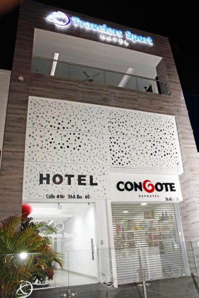 Fachada exterior nocturna del Hotel Travelers Sport con tienda Congote Deportes en primer plano
