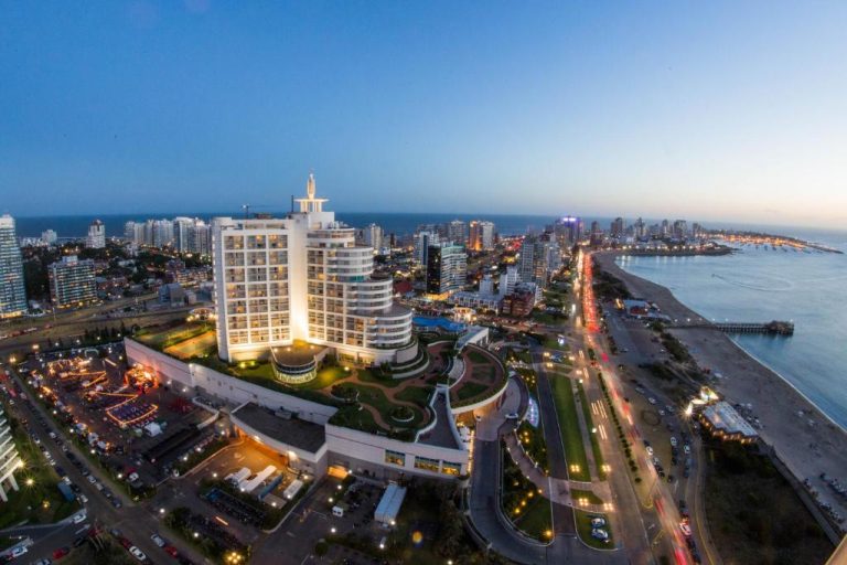 Vista aérea nocturna del Enjoy Punta del Este con su fachada iluminada frente al mar y la rambla
