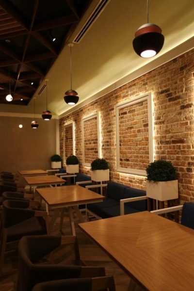 Restaurante interior del Hotel Onogošt con paredes de ladrillo visto, mesas de madera y vegetación decorativa