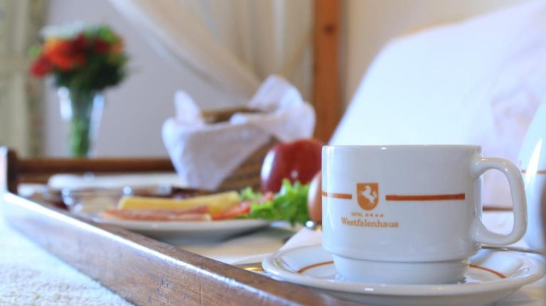 Bandeja de desayuno en cama con café, embutidos y frutas frescas en el Hotel Westfalenhaus
