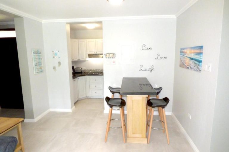 Cocina equipada y zona de comedor con barra alta y taburetes en Beach One Bedroom Suite A22