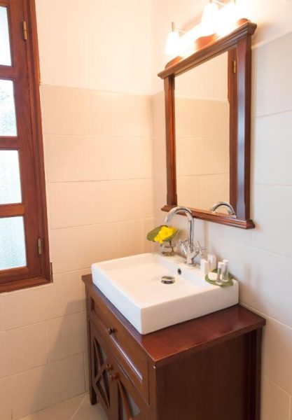 Baño elegante con lavabo sobre mueble de madera y espejo iluminado en Hotel l'Impératrice