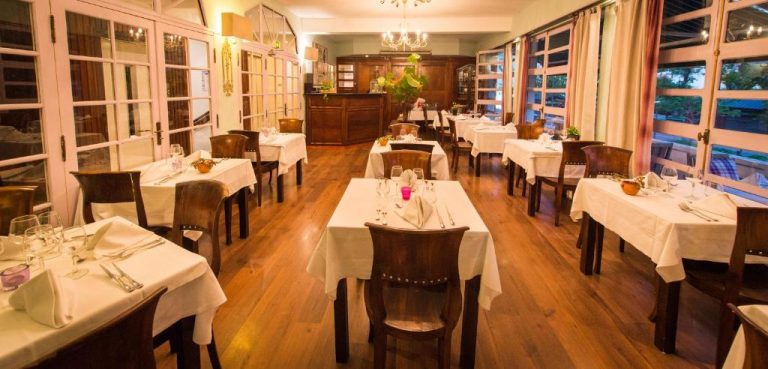 Restaurante interior del Hotel l'Impératrice con mesas vestidas de blanco y suelo de madera