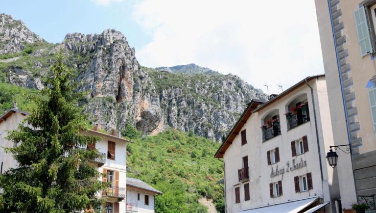 Fachada del Auberge Saint Martin con impresionantes montañas rocosas y vegetación alpina de fondo