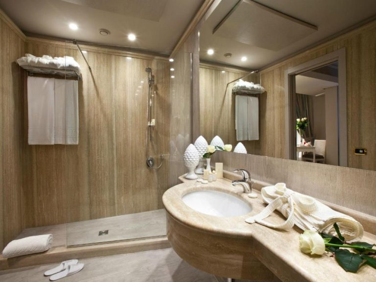 Baño de lujo con ducha de mármol y lavabo elegante en el Grand Hotel Baia Verde