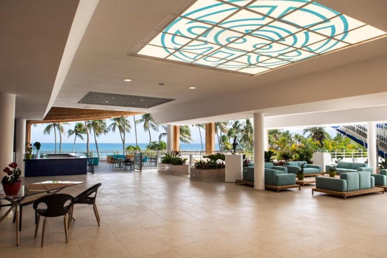 Lobby abierto con vistas al mar y palmeras del Hotel Arawak Beach Resort con zona de descanso