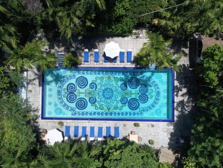Vista aérea de la piscina con mosaico artístico del Graycliff Hotel rodeada de palmeras tropicales