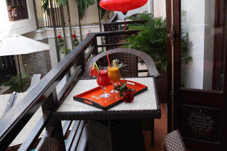 Terraza con cócteles tropicales servidos en bandeja roja en el balcón del Long Life Riverside Hotel