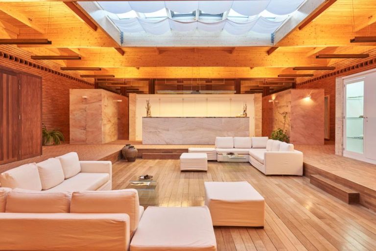 Amplio salón con sofás blancos y techo de madera iluminado en Hotel Porto Santo & Spa