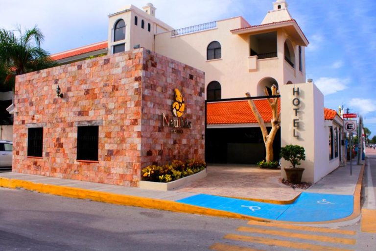 Fachada exterior con entrada principal del Hotel Nautilus, edificio con pared de piedra y señalización