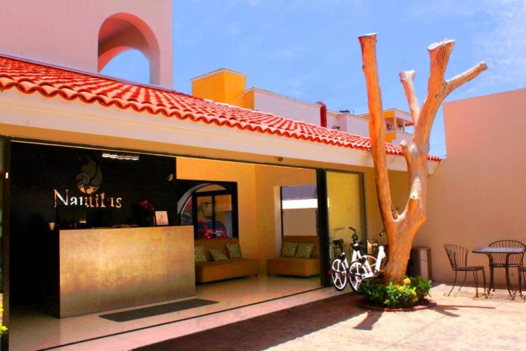 Recepción exterior y entrada principal del Hotel Nautilus con bicicletas y árbol decorativo