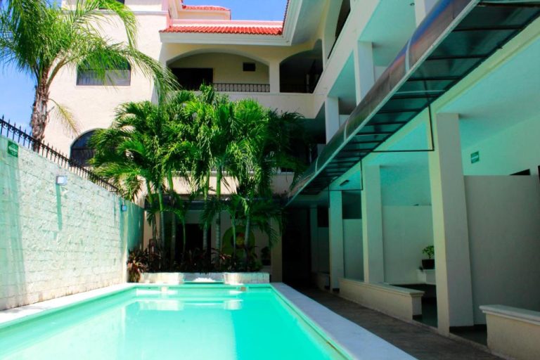 Piscina exterior con palmeras tropicales y terraza del Hotel Nautilus en un día soleado