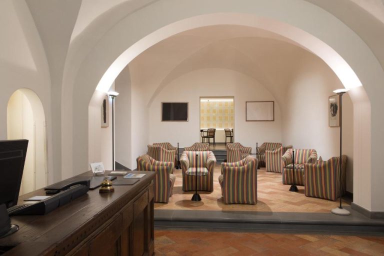 Recepción y lobby con arcos de bóveda y sillones de rayas del Hotel Tiferno